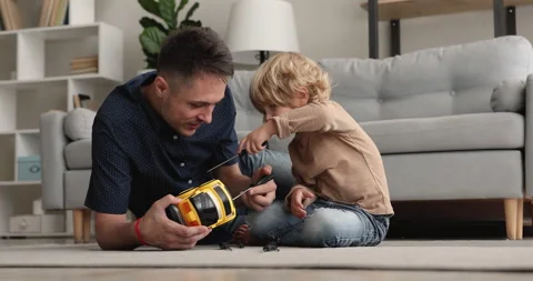 Smiling young father helping little son fixing toy car. Stock Footage