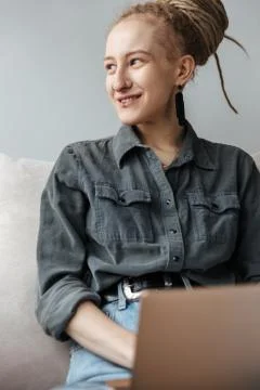Smiling young girl with dreadlocks using laptop computer. Stock Photos