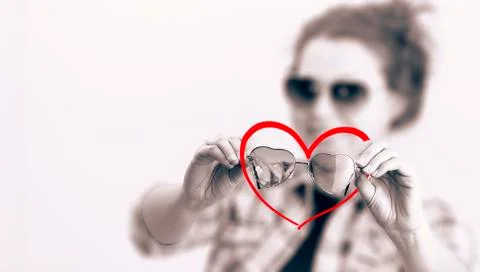 Smiling young girl with  two sunglasses in the form of hearts Foto stock