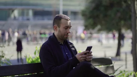 Smiling young guy texting from smartphone. Video stock 102175885