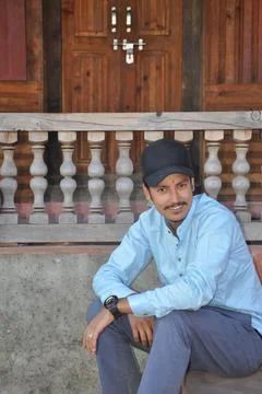 A smiling young guy wearing cap with looking at camera while sitting Stock Photos