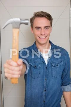 Smiling young handyman holding out hammer Stock Photos