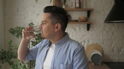 Smiling young healthy bearded guy holding glass, drinking pure fresh water. Stock Footage 139628230