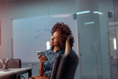 Smiling young lady using mobile phone in the office Stock Photos