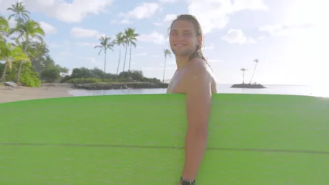 Smiling young long haired Surfer with green Board at Tropical Hawaii Beach Stock Footage 265128344