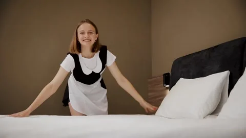 Smiling young maid arranging pillows on a bed, hotel room service housekeeping Stock Footage 324721778