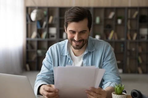 Smiling young male remote employee receive paper letter of accreditation Stock Photos