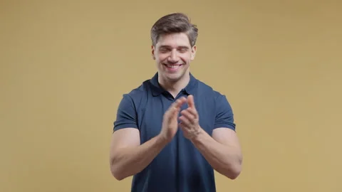 Smiling young man applauding with enthusiasm in a studio portrait. Congratulatio Stock Footage 340422374