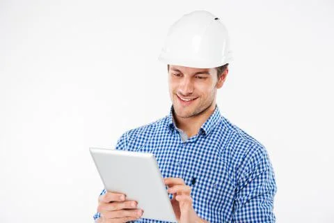 Smiling young man building engineer in helmet using tablet Stock Photos