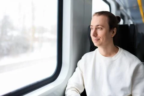Smiling young man with a bun looking out the window while traveling on a mo.. Stock Photos