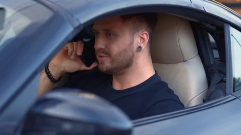 Smiling young man calling by smartphone while driving car Stock Footage 94354306