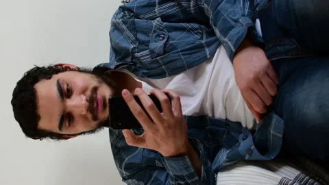 Smiling young man checks content on his mobile, sitting on the sofa Stock Footage 138511675