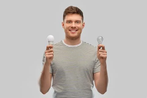 Smiling young man comparing different light bulbs Stock Photos