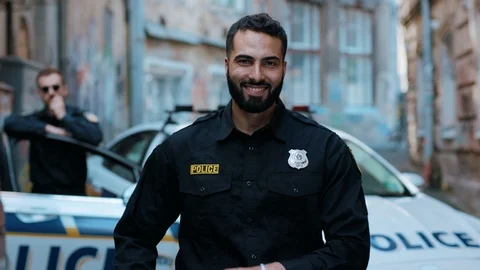Smiling young man cops stand near patrol car look at camera enforcement happy Video stock 113005873