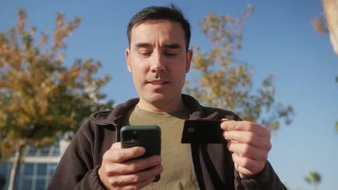 Smiling young man customer holding credit card and smartphone. Happy shopper Stock Footage 277684741