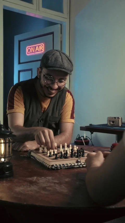 Smiling Young Man in Flat Cap Playing Chess in Retro Studio with On Air Sign Stock Footage 321679976