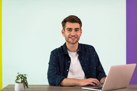 Smiling young man freelancer using laptop studying online working from home Foto stock