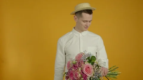 Smiling young man in hat holding flower bouquet 스톡 동영상 125478290