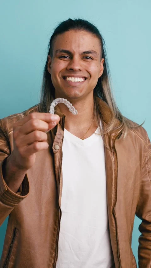 Smiling young man holding an invisible dental aligner. Vertical Stock Footage 339325996