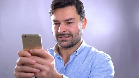Smiling young man holding smart phone and looking at it. Portrait of a happy man Video stock 101634245