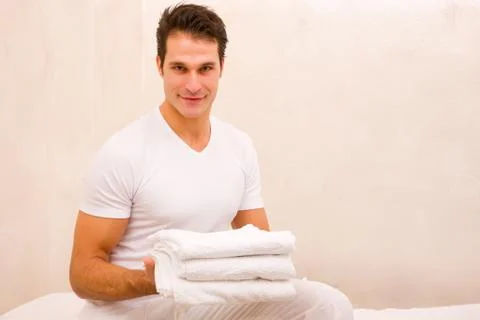 Smiling young man holding stack of towels Stock Photos