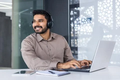 Smiling young man indian programmer and developer working in headphones on 写真素材