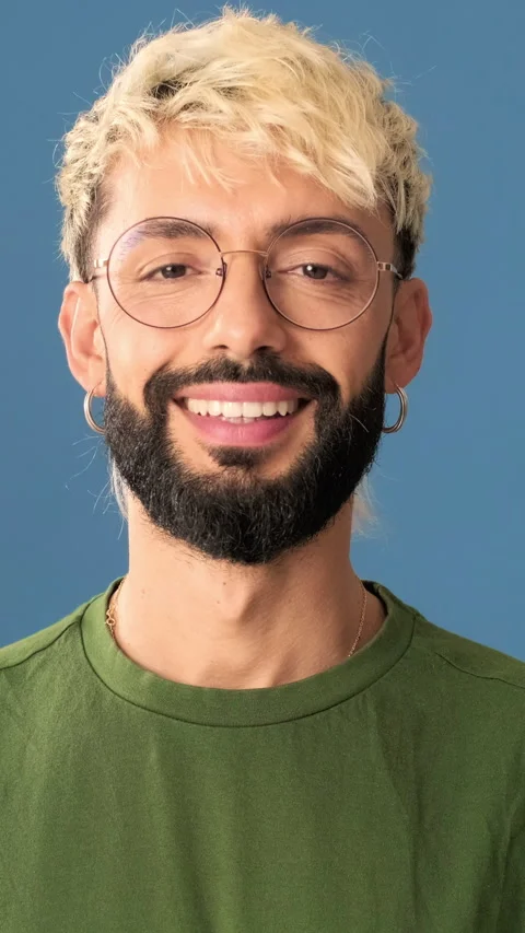Smiling young man looking at camera, isolated on blue background in a studio Stock Footage 297205457