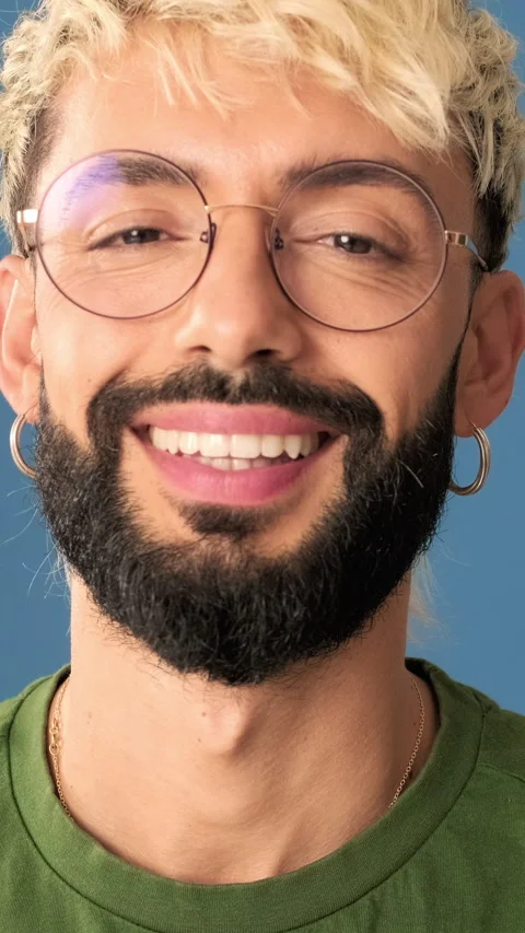 Smiling young man looking at camera, isolated on blue background in a studio, Stock Footage 303288837