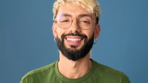 Smiling young man looking at camera, isolated on blue background in a studio, Stock Footage 310850276