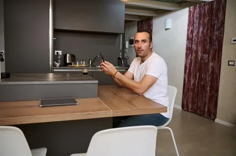 Smiling young man looking at camera while holding credit card, using smartpho Stock Photos