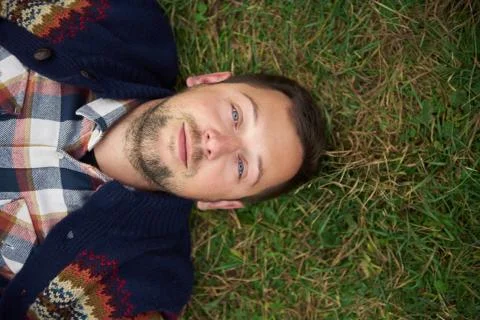 Smiling young man lying on grass in the great outdoors Stock Photos