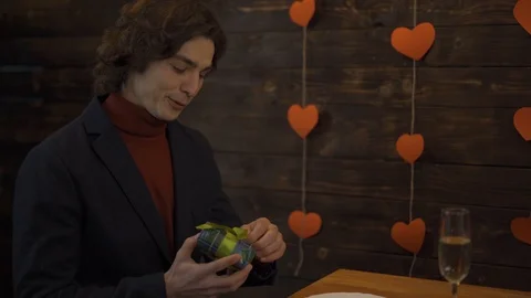 Smiling young man opening gift in valentine day Vidéo 124704624