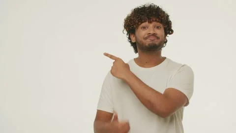 Smiling young man pointing to the side with finger and showing thumbs up Stock Footage 231475699