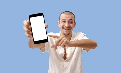 Smiling Young Man Pointing at Smartphone Blank White Screen Mockup on Blue .. Stock-Fotos