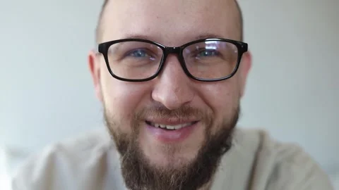 Smiling young man puts on glasses and says Stock Footage 242720511