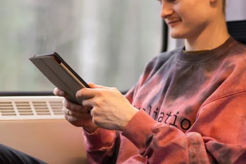 Smiling young man reading e-book when he traveling by train. Man sits at the Stock Photos