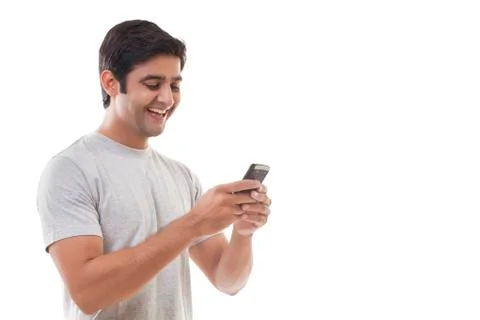 Smiling young man reading text message over white background Stock Photos