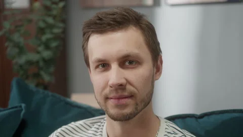 Smiling young man sitting, looking at camera, portrait of handsome male relaxing Stock Footage 150438462