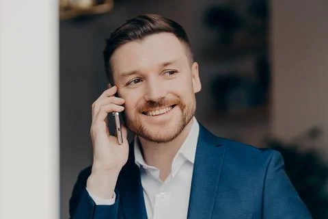 Smiling young man in suit using mobile phone at home Stock Photos