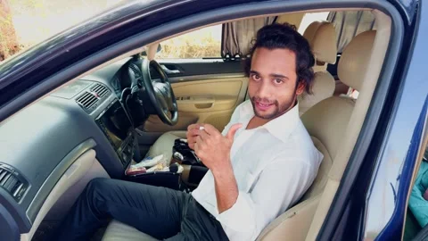 Smiling young man talking and laughing with long hair sitting in a car segr.. Video stock 270200217