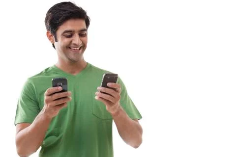 Smiling young man text messaging through cell phones Stock Photos