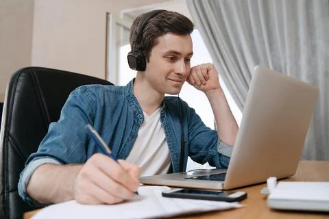 Smiling young man using computer for distance learning in his room Stock Photos