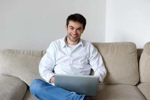 Smiling young man using laptop at home Foto stock