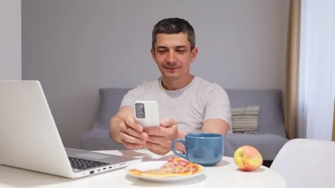 Smiling young man using mobile phone and laptop browsing internet web pages Stock Footage 292759694