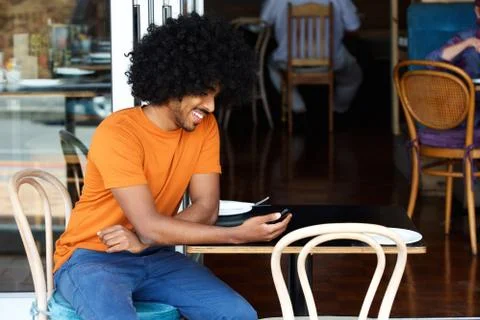 Smiling young man using mobile phone at cafe Foto stock