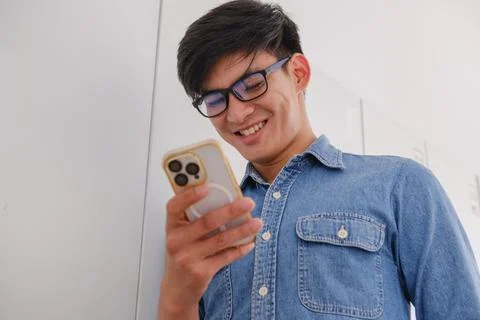 Smiling young man using a smartphone in a modern office Stock Photos