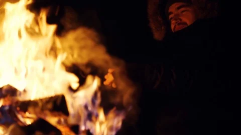 Smiling young man warm hands an open fireplace outdoor at night happy in winter Video stock 105204983
