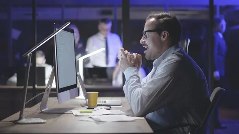 Smiling young man working at the office late at night, using computer Stock Footage 125689373