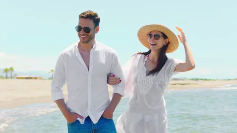 Smiling young pair walking on beach 스톡 동영상 155870646