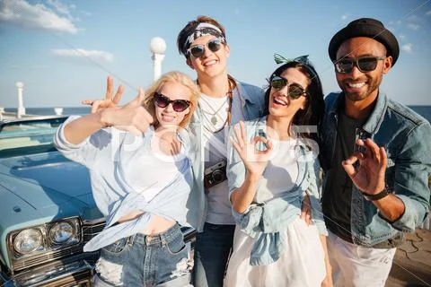 Smiling young people showing ok and thumbs up on promenade Stock Photos